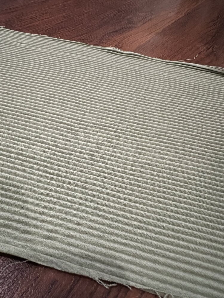 Lembaran kain hasil plisket warna sage green dengan lipatan rapat